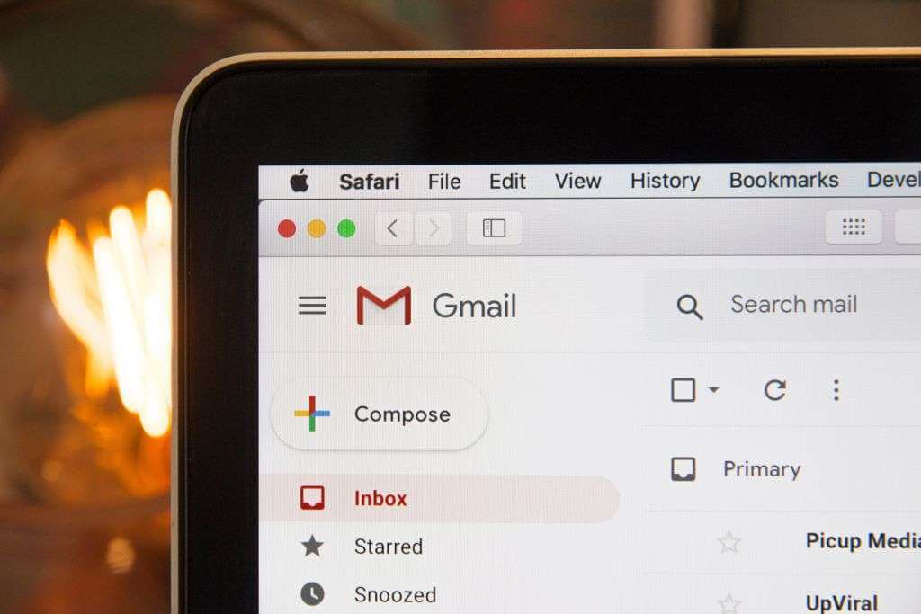 A laptop screen displaying the Gmail interface with the "Inbox" and "Compose" buttons visible, while part of an illuminated light bulb glows in the background, subtly suggesting a seamless blend of creativity and technology akin to TouchDesigner.