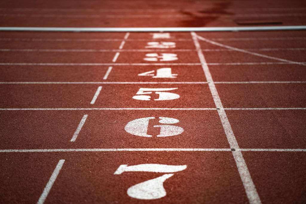 A close-up of a red running track with white lane numbers 1 through 7 and starting lines, reminiscent of a TouchDesigner render.